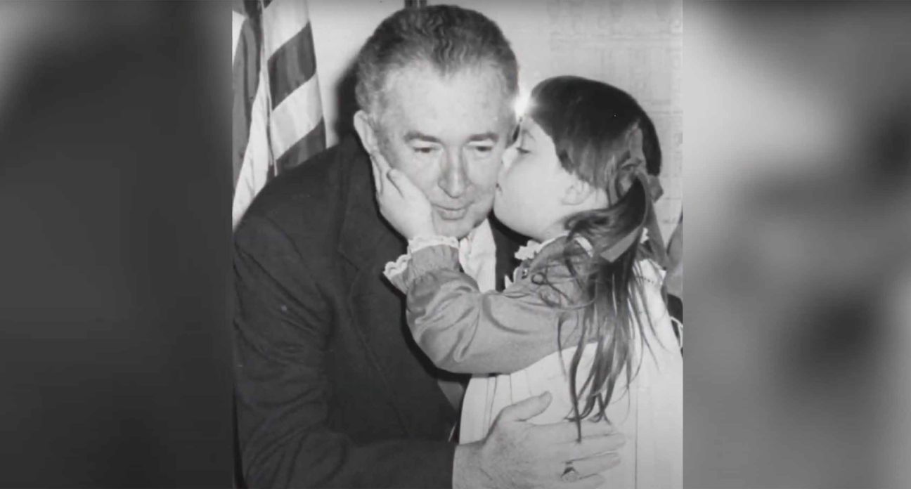 Kid giving a cheek-kiss to her grandfather