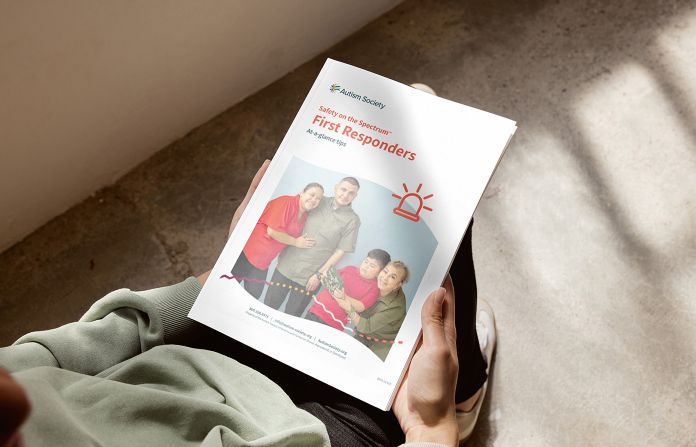 Person holding an Autism Society booklet that covers Safety on the Spectrum First Responders